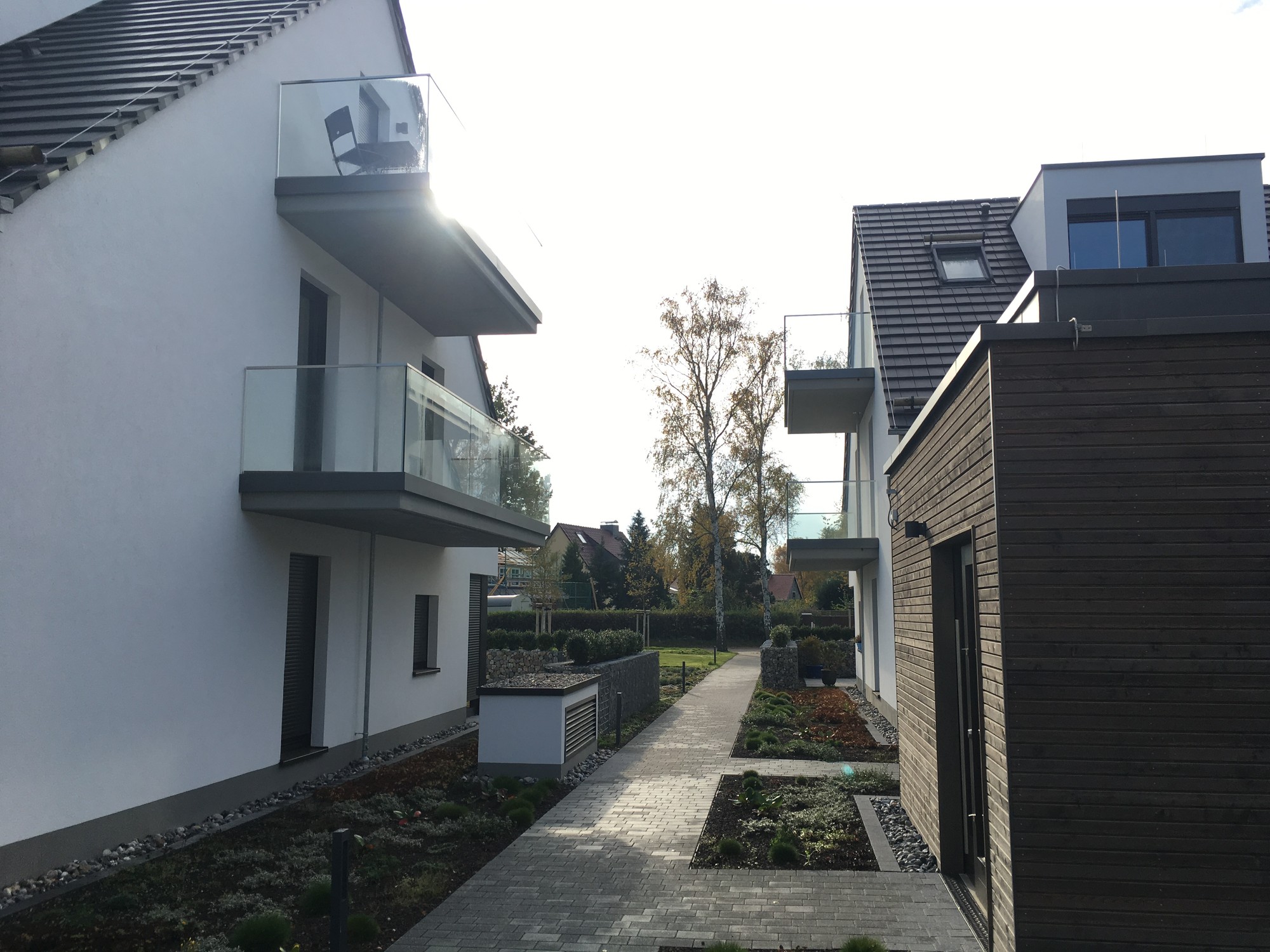 Moderne weiße Villa mit mehreren Balkonen aus Ganzglasgeländer im Garten – Auftrag Wandlitz